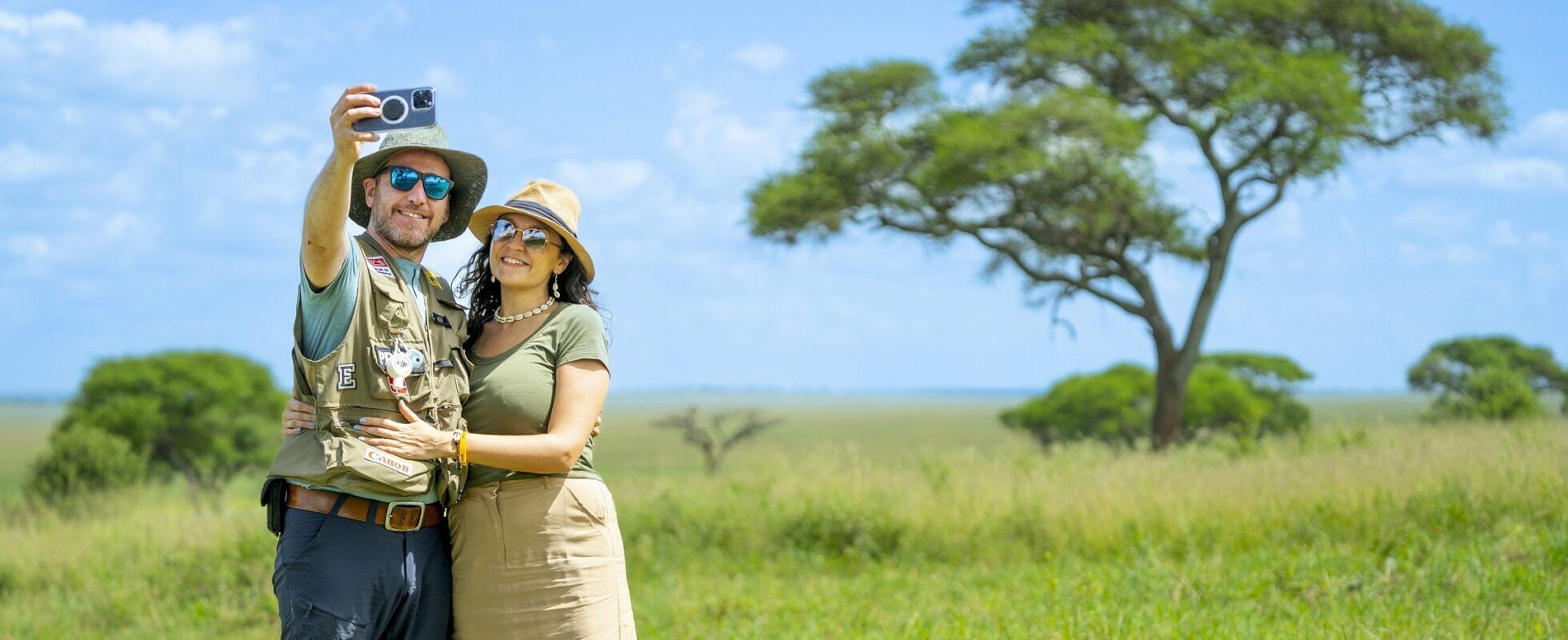 Un couple en Tanzanie prenant un selfie devant un acacia.